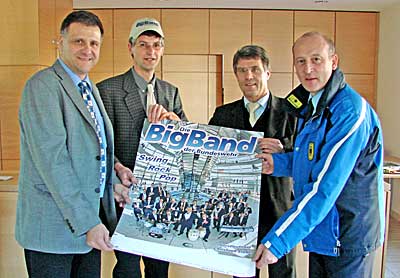 Edgar Seitnborn, Reiner Friedsam, Wolfgang Kröger und Thomas Ernst präsentieren das Plakat der BigBand der Bundeswehr im Gemeindehaus St. Peter.