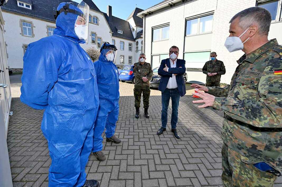 Landrat Dr. Jürgen Pföhler (Mitte) und Generalstabsarzt Dr. Stephan Schmidt (rechts) im Gespräch mit zwei Soldaten, die im Corona-Abstrichzentrum in Grafschaft-Gelsdorf