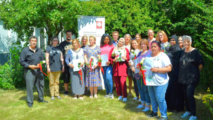 Glücklich halten die Absolventinnen und Absolventen ihre Zertifikate und Rosen in den Händen. Mit dem Abschluss im Bereich qualifizierende Vorbereitung zur Alten- & Krankenpflegehilfeausbildung und Betreuungsassistenz haben sie ihren beruflichen Weg gefunden. Foto: Eberhard Thomas Müller