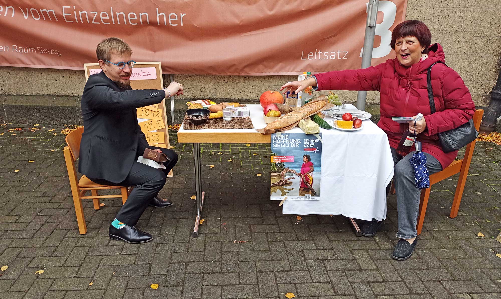 Pfr. Heiko Marquardsen und Christiane Langen - Auf einem Kinderstuhl sitzend erreicht man die Fülle auf dem gedeckten Tisch nicht. Foto: Walburga Greiner