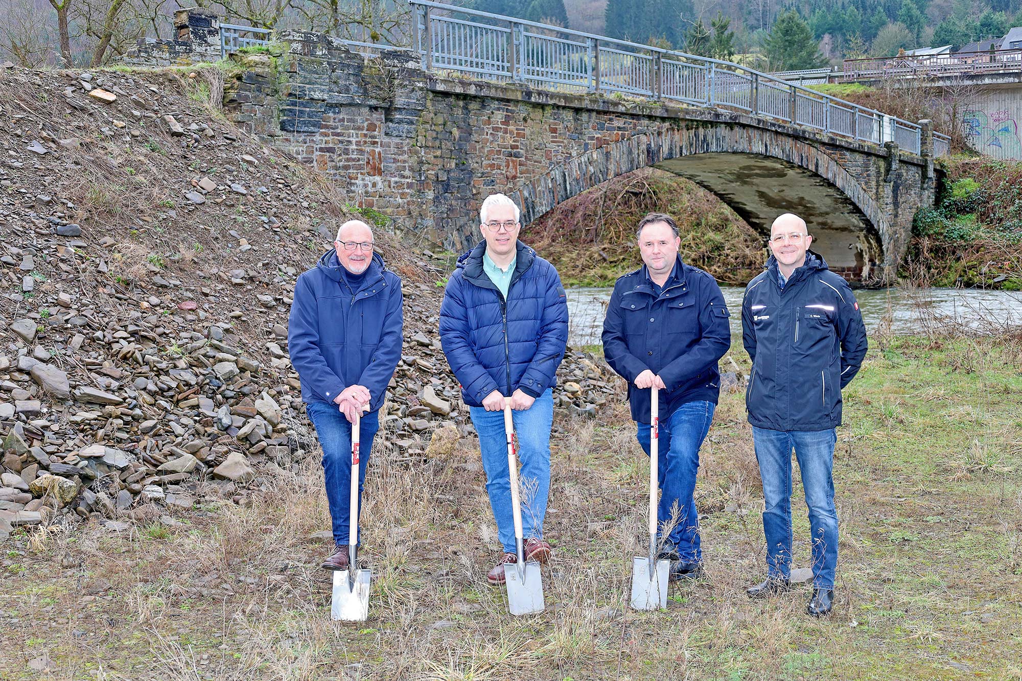 Jürgen Schwarzmann, Ortsbürgermeister von Hönningen, Dominik Gieler, Bürgermeister der Verbandsgemeinde Altenahr, Olaf Heimermann und Clemens Wecke vom Regionalbüro Ahr des Planungsbüros Julius Berger International leiteten mit dem ersten Spatenstich die Erstellung der Baustellenstraße sowie den flutbedingten Rück- und Neubau der Brücke „Vor Kiehren“ in Hönningen ein. Foto: Thorsten Trütgen / VG Altenahr