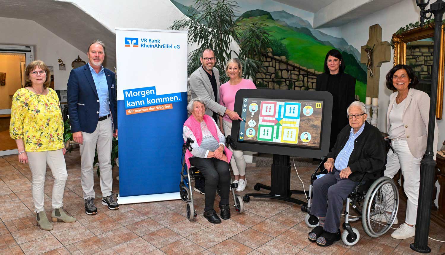 Ralf Schneider (Firmenkundenbetreuer der VR Bank RheinAhrEifel eG) und Thomas Theisen (Direktor des Regionalmarkts AhrBrohltal der VR Bank RheinAhrEifel eG) bei der Übergabe des CareTables an die Vorsitzende des Fördervereins, Cornelia Adams, sowie an die Bewohnerinnen und Bewohner der Villa Romantica. Foto: Peter Seydel
