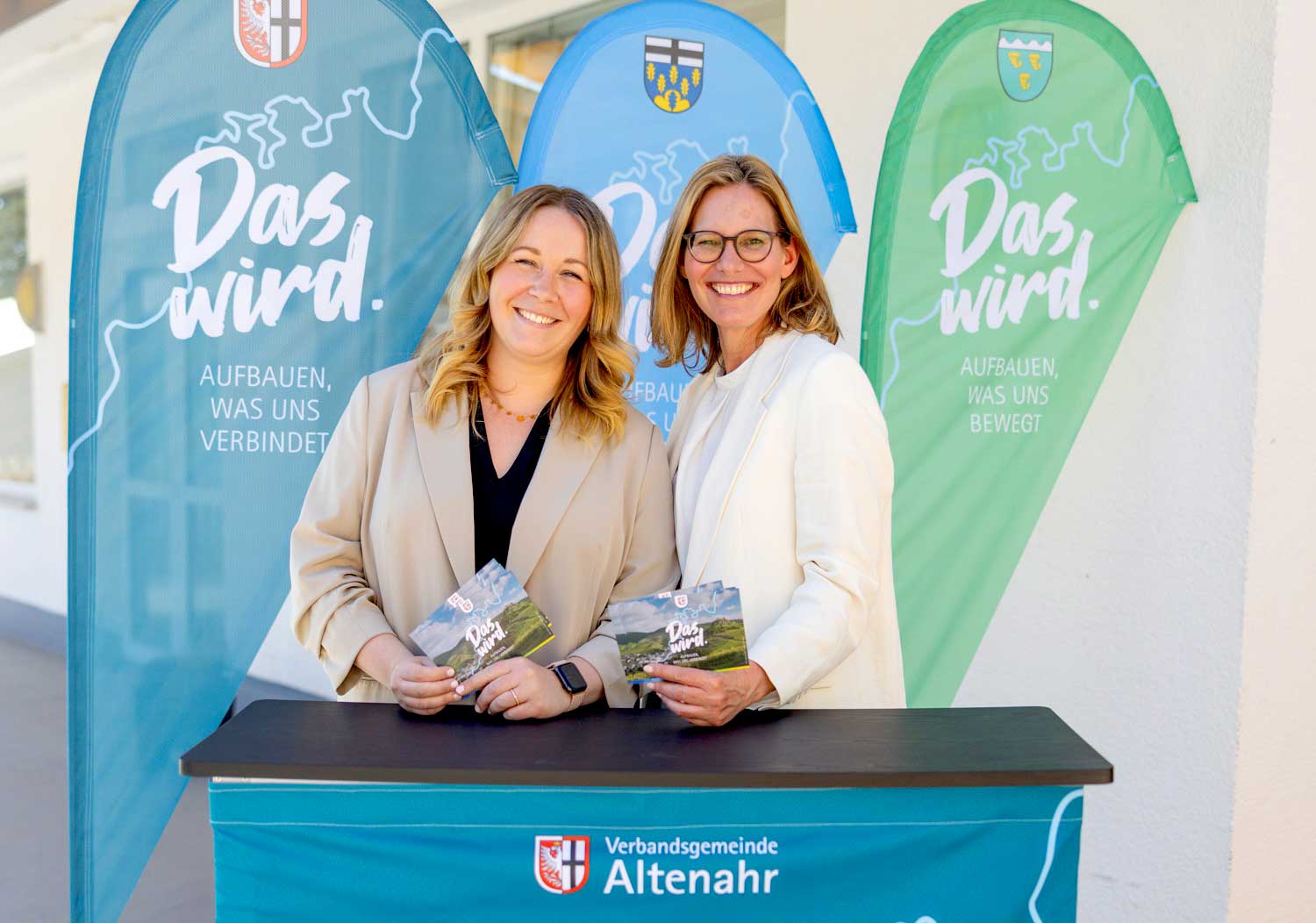 Marianne Reiß (li.) und Julia Jonas freuen sich auf regen Besuch am Wiederaufbau-Infostand am 15.6.2025 während der Tour de Ahrtal am Aktionspunkt in Liers. (Foto: ifok GmbH / Nadine Norman)